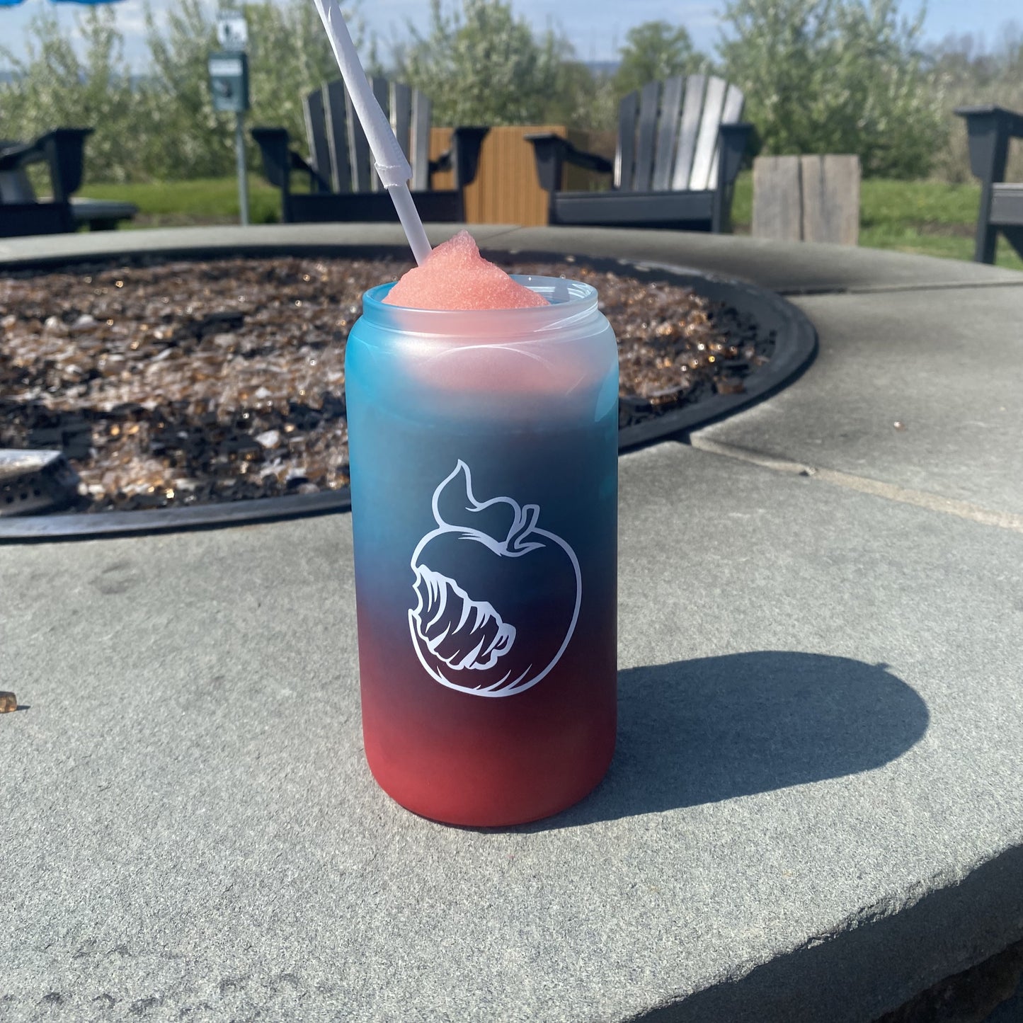 A frosted 16oz can-shaped glass with a pink-to-mint ombre gradient. One side shows the Angry Orchard logo with "Walden, New York" text; the other side features the brand's signature bitten apple icon. In a third image, the glass is filled with a frozen drink, revealing a bright red-to-blue ombre color change.